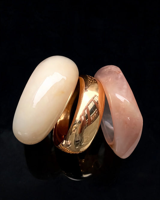 Bracelete Deusa do Mar: trio de pulseiras em resina creme, dourada e rosé, sobre fundo preto