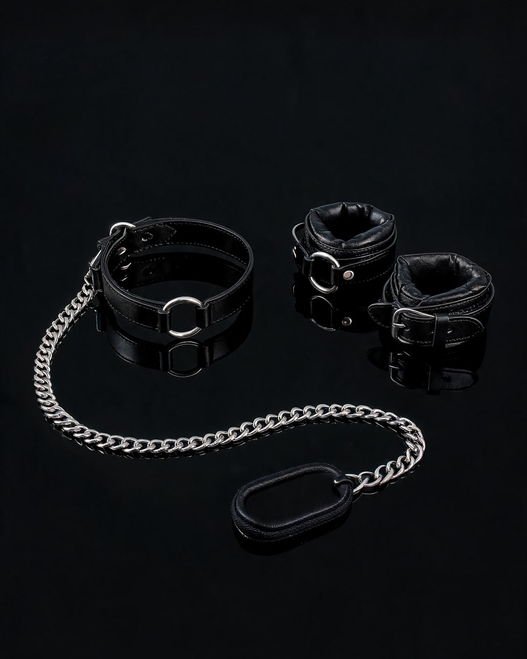 Kit Sexy Woman em couro sintético preto: coleira com argola, guia de corrente e algemas, sobre fundo preto