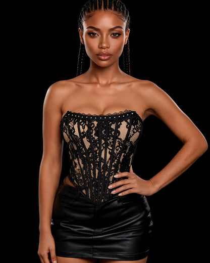 Corselet Madona tomara que caia em renda preta sobre nude com barbatanas e tachinhas, em modelo de frente sobre fundo preto
