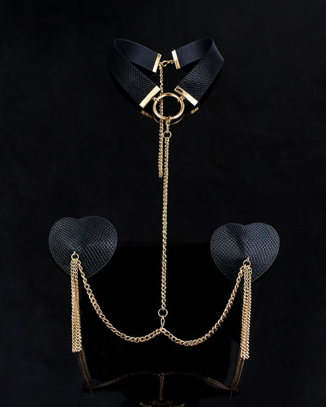 Madonna Nipple Stickers: choker preto com argola dourada, corrente e capas de coração pretas com franjas douradas, sobre fundo preto